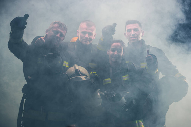 消防署内で消火器の煙の真ん中に立つ消防団 - 写真・画像