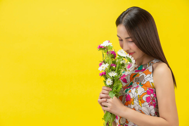 beautiful woman smelling white flower on yellow background - Zdjęcie, obraz