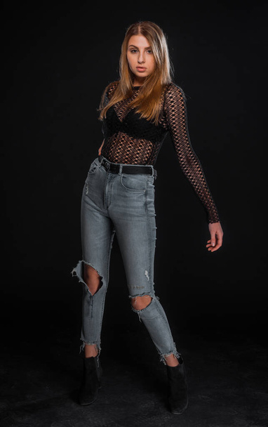 Studio fashion shot of a good looking girl wearing denim jeans and black top - Foto, afbeelding