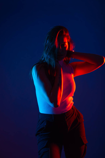 Γυναικείο μοντέλο ποζάρει σε studio με κόκκινα και μπλε χρώματα σε υψηλή αντίθεση. - Φωτογραφία, εικόνα