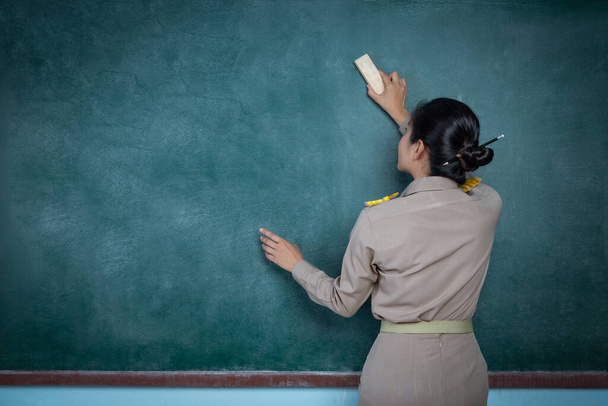 thai woman teacher in officail outfit erasing backbord - Fotografie, Obrázek