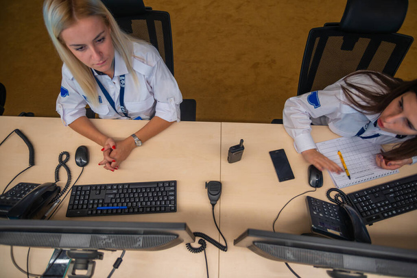 Női biztonsági őrök dolgoznak számítógépek, miközben ül a fő vezérlőteremben - Fotó, kép