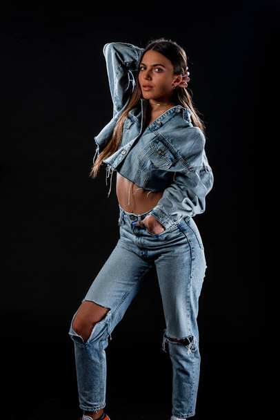 Body shot of a stylish woman posing in ripped trendy jeans and denim jacket - Foto, Imagem