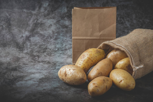 Potatoes pour out of sacks on gray floor - Photo, Image