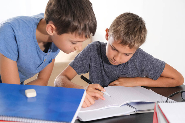 Lernen zu Hause, selbstbestimmtes Konzept. Kinder zu Hause machen Hausaufgaben mit Heften und denken darüber nach, wie man Mathe-Aufgaben macht - Foto, Bild