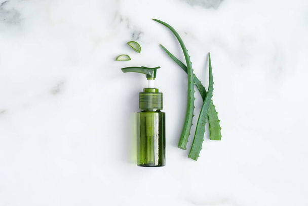 Aloe vera cosmetic bottle and plant leaves on marble desk. Natural organic beauty product, skin care concept. Flat lay, top view. - Foto, Bild