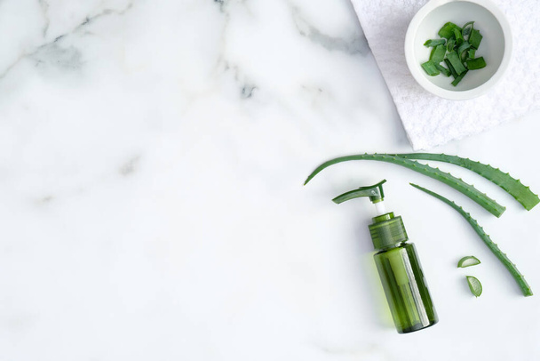 Natural organic SPA cosmetic product. Top view aloe vera gel and sliced plant leaves on marble background. Skincare, cosmetology, dermatology concept - Foto, imagen