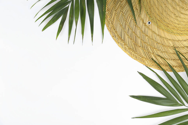 Зелене пальмове листя з широким цегляним солом'яним капелюхом як літні символи, пляжний одяг на паперовому текстурованому фоні з великою кількістю місця для тексту. Вид зверху, плоский ліжко
. - Фото, зображення