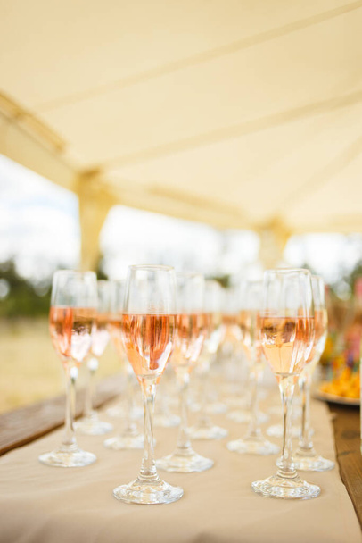 Elegantes copas con champán de pie en una fila en la mesa de servicio durante la fiesta o la celebración
 - Foto, imagen