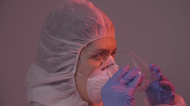 Professionele vrouwelijke arts in masker staat in het ziekenhuis kamer zetten bril op. Gezondheidszorgconcept. Laboratoriummedewerker - Video