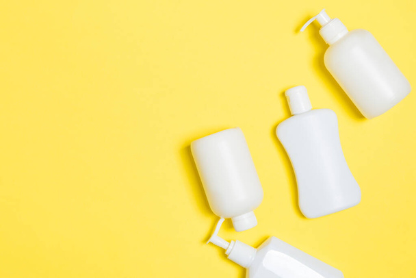 Set of White Cosmetic containers isolated on yellow background, top view with copy space. Group of plastic bodycare bottle containers with empty space for you design. - Valokuva, kuva