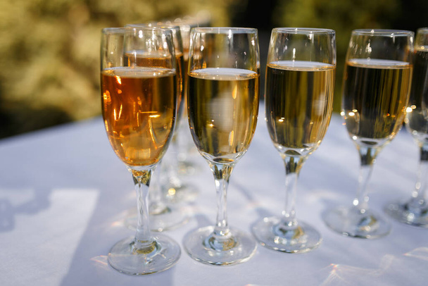 Elegant glasses with champagne standing in a row on serving table during party or celebration - Foto, Imagen