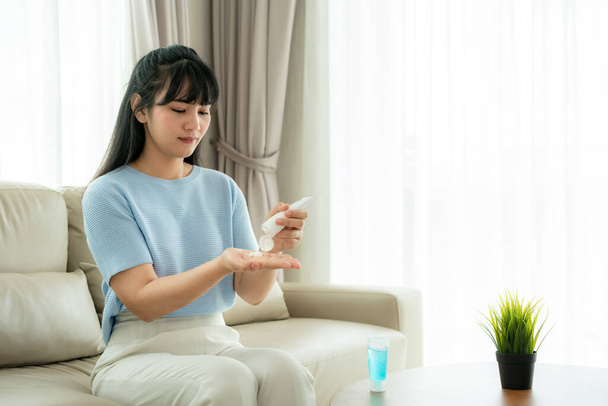 Mujer asiática usando loción o hidratar como mano de su vida diaria para la protección de la piel a secarse e irritarse después de usar alcohol gel antiséptico, prevención, limpieza de las manos infección
. - Foto, imagen