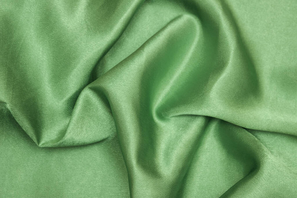 Glatte, elegante grüne Seiden- oder Satin-Textur kann als abstrakter Hintergrund verwendet werden. Zerknittertes Gewebe. - Foto, Bild
