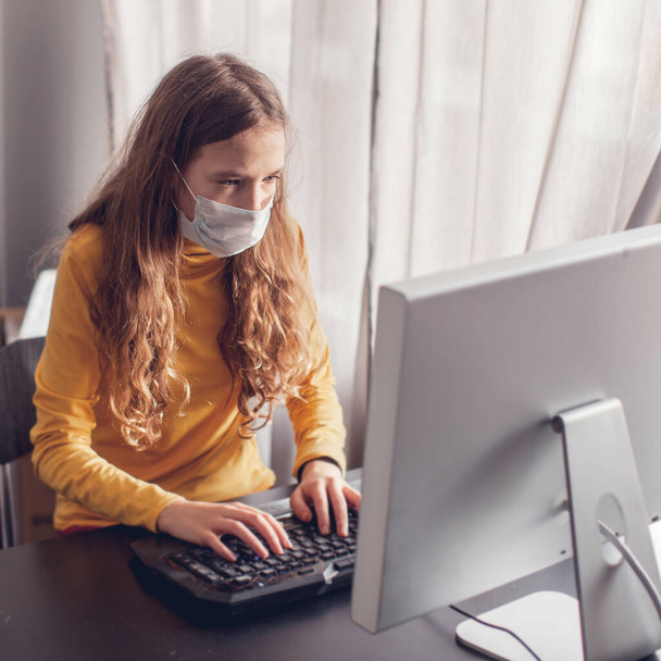 Teen gaming at home with computer, wearing protective mask - Foto, Bild