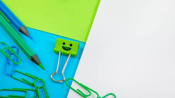 Clip di carta per ufficio verde e blu, clip per raccoglitori di sorrisi e matite sul blocco note
 - Foto, immagini