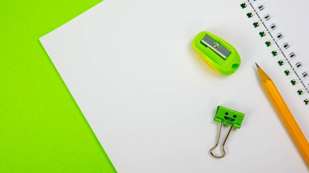 Zielony Temperówka, żółty ołówek i Smiles Binder Clip na notatniku szkolnym - Zdjęcie, obraz
