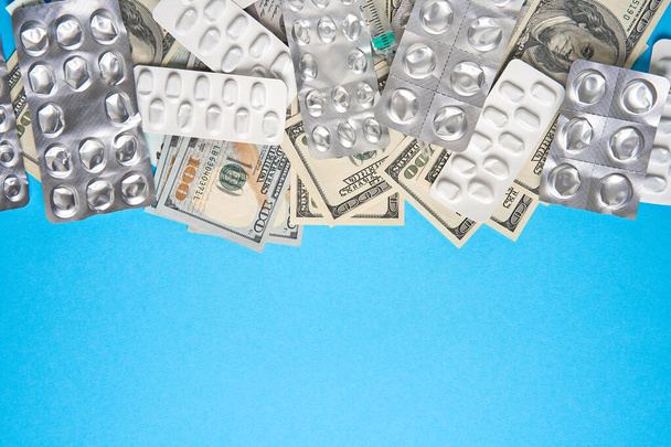 pills empty blisters for drugs individual syringe and money lie on a blue background Expensive medicine health insurance concept. Expensive treatment of diseases. Budget for medical expenses. - Photo, image