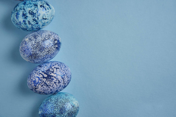 Beautiful blue easter eggs lie in a row on a blue paper background. Easter background. Seasonal holiday flat lay with free space for text. Classic blue color of the year 2020 - Valokuva, kuva