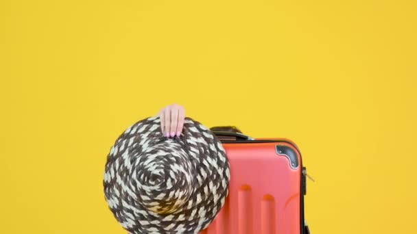 Girl's hands hold a hat and a medical mask clothe on a suitcase. Torn vacation. Isolated on a yellow background. ealth care and medical concept. - Séquence, vidéo