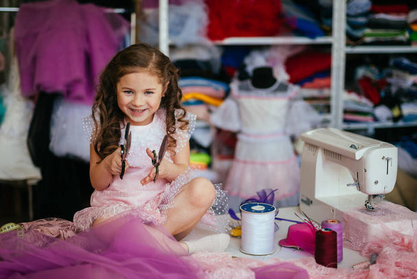 positive girl holds scissors in her hands. Sewing workshop concept - Photo, image