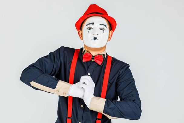 Clown met rode bretels en rode hoed op witte achtergrond. - Foto, afbeelding
