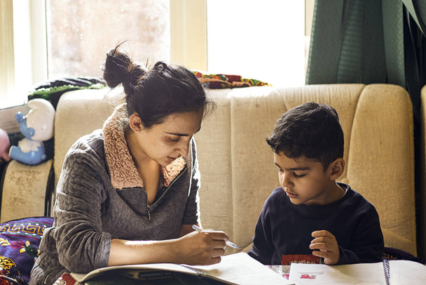 Aide parentale pour les devoirs. Authentique photo de jeune mère aidant son petit garçon à faire ses devoirs
 - Photo, image