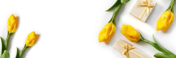 Beautiful bouquet of yellow tulips with golden gift boxes and ribbons on white background - Foto, imagen