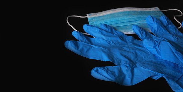 Blue medical sterile mask and blue sterile gloves isolated on a black background. - Photo, Image