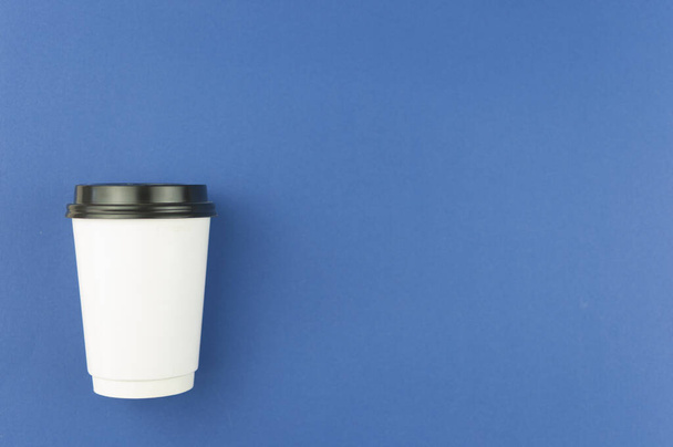 Eldobható fehér kávé csésze kék háttérrel. Felülnézet másolási hellyel - Fotó, kép