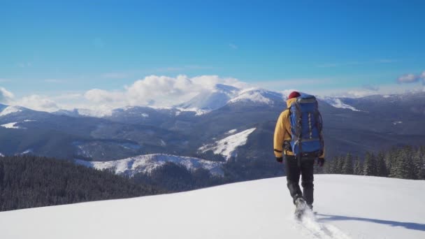 Человек с рюкзаком путешествует по горам зимой - Кадры, видео