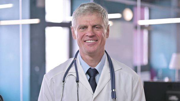 Porträt eines fröhlichen Arztes mittleren Alters, der in die Kamera lächelt - Foto, Bild