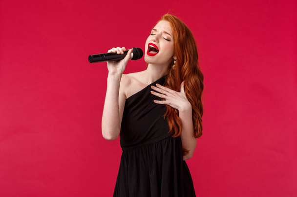 Detailní portrét vášnivé krásné zpěvačky zpívat písně, nosit černé večerní šaty, zavřít oči a ukázat své pocity prostřednictvím hudby, držet mikrofon, navštěvovat karaoke na dívčí noc - Fotografie, Obrázek