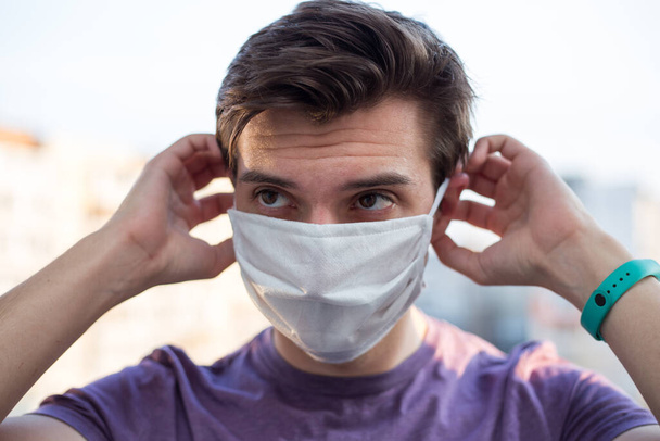 Een jonge vent met een Europees uiterlijk draagt een medisch masker. - Foto, afbeelding