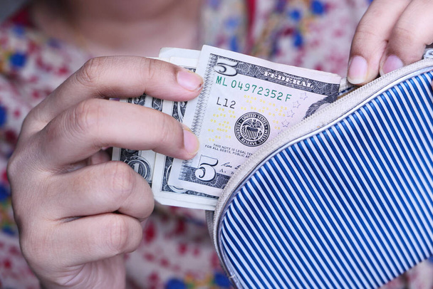 Frau zieht US-Dollar-Scheine aus Geldbörse - Foto, Bild