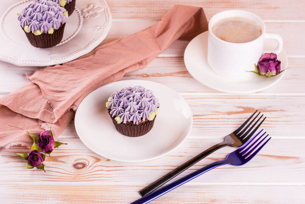 Csokoládé finom cupcake tejszínnel és illatos kávé tejjel egy fehér fa asztalon. Fehér ételek desszertnek - Fotó, kép