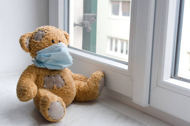 Sick teddy bear in home quarantine wearing a medical mask against viruses during coronavirus and flu outbreak. - Photo, Image