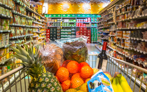 Süpermarketteki market arabası müşterilerin bakış açısından bakılan gıda ürünleriyle dolu. - Fotoğraf, Görsel