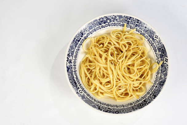 ένα πιάτο με φρέσκα μακαρόνια με ελαιόλαδο στο λευκό πιάτο που απομονώνεται σε λευκό φόντο - Φωτογραφία, εικόνα