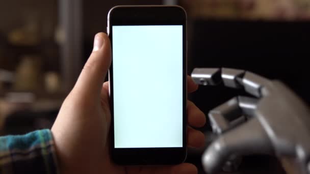 Cyborg utilise le téléphone. Gris main mécanique glisser vers le bas sur smartphone avec écran blanc. Modèle de modèle. - Séquence, vidéo