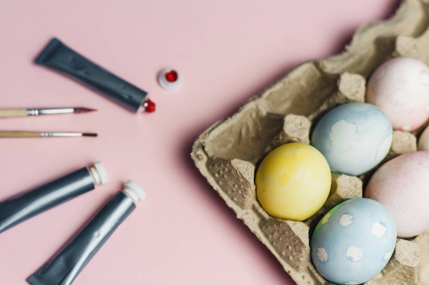 Концепция раскраски пасхальных яиц в пастельные акварельные цвета. Краски и кисти для раскраски яиц на Пасху на розовом фоне
 - Фото, изображение