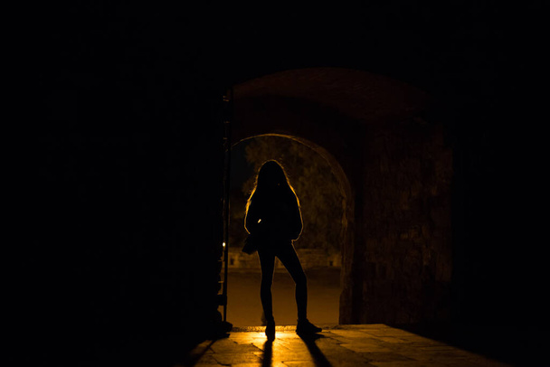 Silhouette eines Mädchens, das vor einer Lichtquelle steht - Foto, Bild