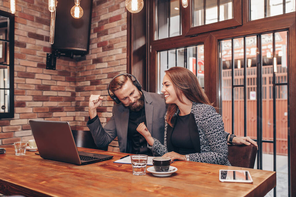Boldog üzletemberek ünneplik siker nézi laptop képernyőn, miközben ül a kávézóban. Sikeres vállalati partnerek és munkatársak, győztesek izgatott győzelem - Fotó, kép