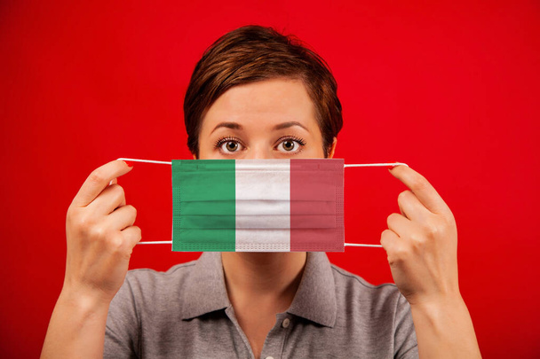 Coronavirus COVID-19 in Italy. Woman in medical protective mask with the image of the flag of Italy. The concept of preventing the spread of the epidemic and treating coronavirus. - Valokuva, kuva