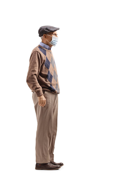 Full length profile shot of a senior man with a protective medical face mask isolated on white background - Valokuva, kuva