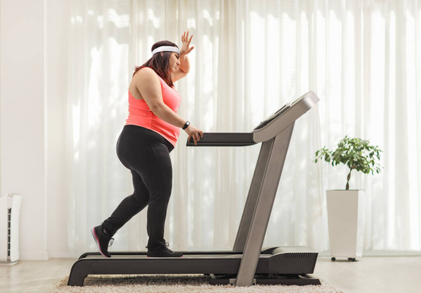 Full length profile shot of a tired overweight woman exercising on a treadmill at home - Fotoğraf, Görsel