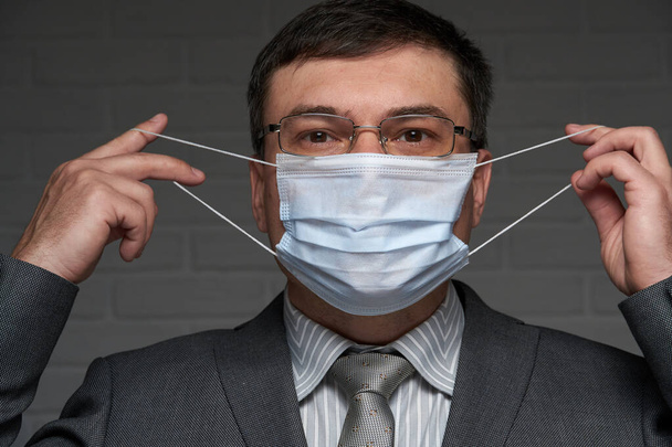 Bir adam antivirüs bireysel korunması için yüzüne maske takar - sağlık ve tıp konsepti, önleme ipuçları - Fotoğraf, Görsel