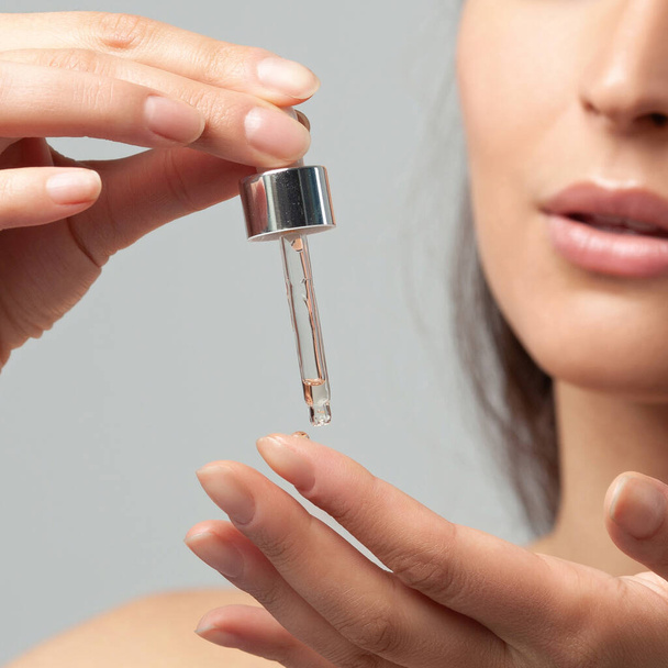 Hands of young woman with a pipette closeup.  Skin care and age cosmetics - Photo, Image