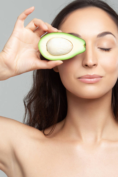Young beautiful woman holding avocado.  Beauty, youth, skin care - 写真・画像