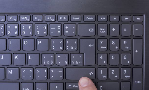 Палец на клавиатуре современного тонкого легкого ноутбука
 - Фото, изображение